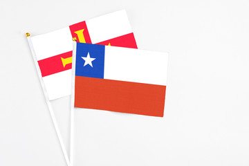 Chile and Guernsey stick flags on white background. High quality fabric, miniature national flag. Peaceful global concept.White floor for copy space.