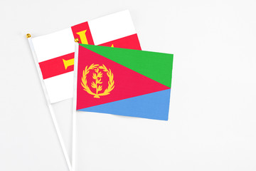 Eritrea and Guernsey stick flags on white background. High quality fabric, miniature national flag. Peaceful global concept.White floor for copy space.