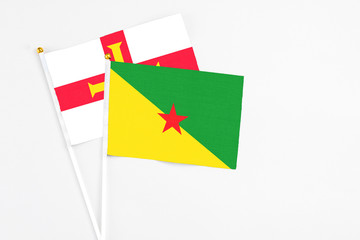 French Guiana and Guernsey stick flags on white background. High quality fabric, miniature national flag. Peaceful global concept.White floor for copy space.