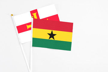 Ghana and Guernsey stick flags on white background. High quality fabric, miniature national flag. Peaceful global concept.White floor for copy space.
