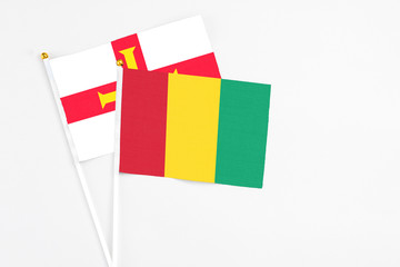 Guinea and Guernsey stick flags on white background. High quality fabric, miniature national flag. Peaceful global concept.White floor for copy space.