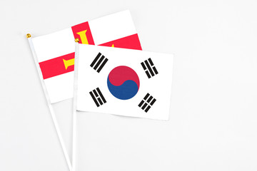 South Korea and Guernsey stick flags on white background. High quality fabric, miniature national flag. Peaceful global concept.White floor for copy space.