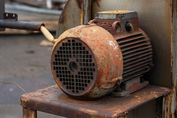 An old rusty working engine stands on a locksmith's chair. exhaust system engine. factory roof