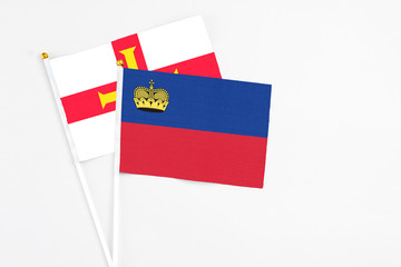 Liechtenstein and Guernsey stick flags on white background. High quality fabric, miniature national flag. Peaceful global concept.White floor for copy space.