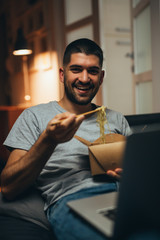 man eating chinese food relaxed in sofa at his home
