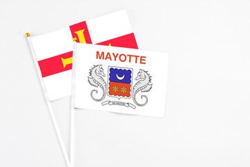 Mayotte and Guernsey stick flags on white background. High quality fabric, miniature national flag. Peaceful global concept.White floor for copy space.