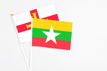 Myanmar and Guernsey stick flags on white background. High quality fabric, miniature national flag. Peaceful global concept.White floor for copy space.