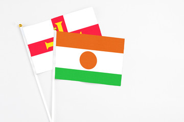 Niger and Guernsey stick flags on white background. High quality fabric, miniature national flag. Peaceful global concept.White floor for copy space.