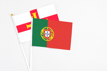 Portugal and Guernsey stick flags on white background. High quality fabric, miniature national flag. Peaceful global concept.White floor for copy space.