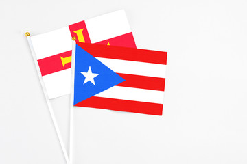 Puerto Rico and Guernsey stick flags on white background. High quality fabric, miniature national flag. Peaceful global concept.White floor for copy space.