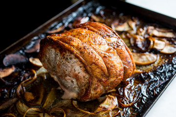 Cider roasted pork loin with apples and chili peppers on baking sheet