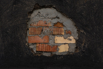 texture wall. plaster carelessly painted with black paint, stains from the brush are visible. in the center, the plaster is broken, and most of the brick wall is visible. red and white brick
