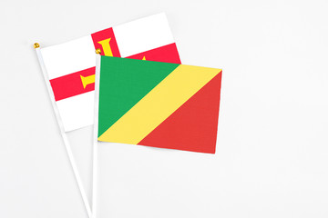 Republic Of The Congo and Guernsey stick flags on white background. High quality fabric, miniature national flag. Peaceful global concept.White floor for copy space.