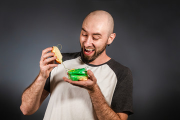 Environmental pollution and food industry. Portrait of a bald man with a beard, who looks with admiration at the garbage filling of an open hamburger