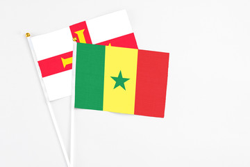 Senegal and Guernsey stick flags on white background. High quality fabric, miniature national flag. Peaceful global concept.White floor for copy space.