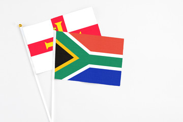 South Africa and Guernsey stick flags on white background. High quality fabric, miniature national flag. Peaceful global concept.White floor for copy space.