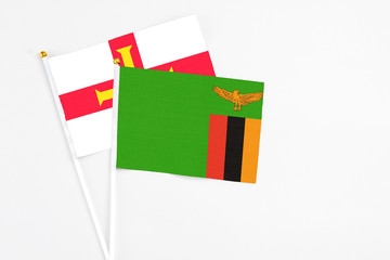 Zambia and Guernsey stick flags on white background. High quality fabric, miniature national flag. Peaceful global concept.White floor for copy space.