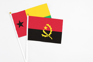 Angola and Guinea Bissau stick flags on white background. High quality fabric, miniature national flag. Peaceful global concept.White floor for copy space.