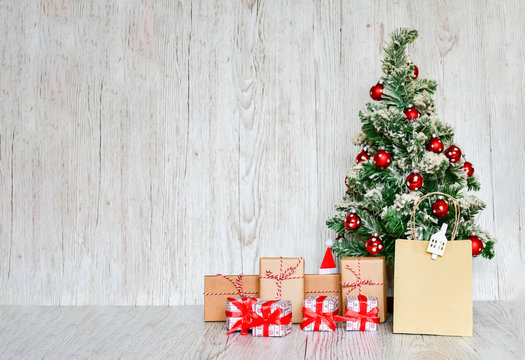 Selective focus Christmas tree with set of gift boxes tight with red ribbins, handmade objects on wood gray background. Christmas holiday concept.