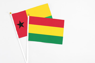 Bolivia and Guinea Bissau stick flags on white background. High quality fabric, miniature national flag. Peaceful global concept.White floor for copy space.
