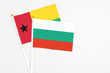 Bulgaria and Guinea Bissau stick flags on white background. High quality fabric, miniature national flag. Peaceful global concept.White floor for copy space.