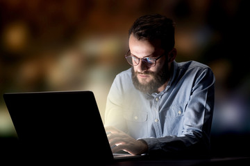 Young handsome businessman working late at night in the office