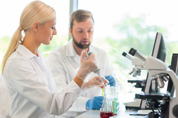 Scientist working in lab. Doctors making medical research. Biotechnology, chemistry, science, experiments and healthcare concept. Day light and window background.