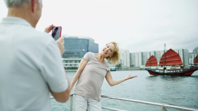 Happy Caucasian couple taking pictures Hong Kong harbor