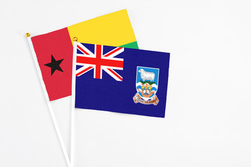 Fototapeta premium Falkland Islands and Guinea Bissau stick flags on white background. High quality fabric, miniature national flag. Peaceful global concept.White floor for copy space.