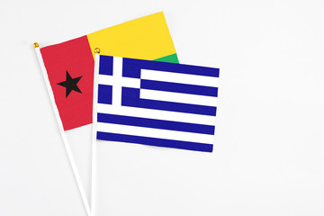 Greece and Guinea Bissau stick flags on white background. High quality fabric, miniature national flag. Peaceful global concept.White floor for copy space.