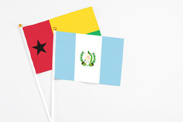 Guatemala and Guinea Bissau stick flags on white background. High quality fabric, miniature national flag. Peaceful global concept.White floor for copy space.