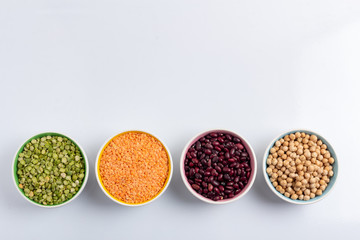 Dried beans, lentils, green horn and chickpeas in round plates on a white background