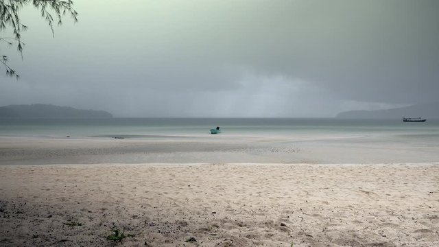 Dark rainy clouds over sand beach shore is filled with mist and rain as backdrop
