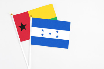 Honduras and Guinea Bissau stick flags on white background. High quality fabric, miniature national flag. Peaceful global concept.White floor for copy space.