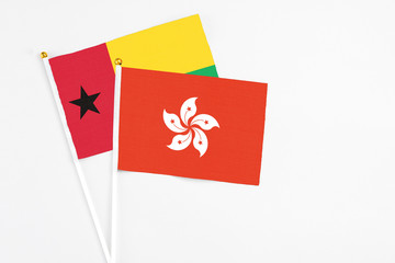 Hong Kong and Guinea Bissau stick flags on white background. High quality fabric, miniature national flag. Peaceful global concept.White floor for copy space.