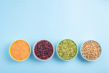 Dried beans, lentils, green horn and chickpeas in round plates on a blue background