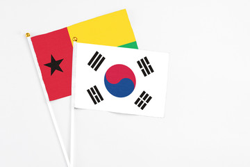 South Korea and Guinea Bissau stick flags on white background. High quality fabric, miniature national flag. Peaceful global concept.White floor for copy space.