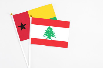 Lebanon and Guinea Bissau stick flags on white background. High quality fabric, miniature national flag. Peaceful global concept.White floor for copy space.