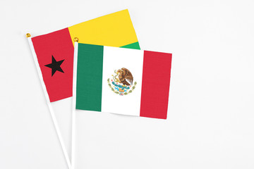 Mexico and Guinea Bissau stick flags on white background. High quality fabric, miniature national flag. Peaceful global concept.White floor for copy space.