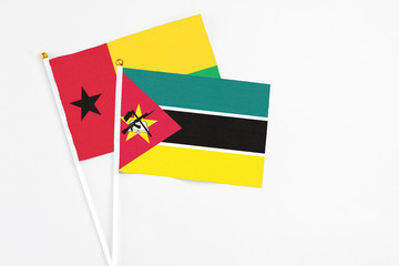 Mozambique and Guinea Bissau stick flags on white background. High quality fabric, miniature national flag. Peaceful global concept.White floor for copy space.