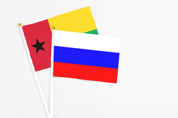 Russia and Guinea Bissau stick flags on white background. High quality fabric, miniature national flag. Peaceful global concept.White floor for copy space.