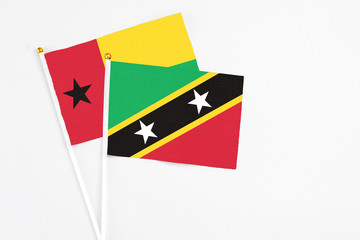 Saint Kitts And Nevis and Guinea Bissau stick flags on white background. High quality fabric, miniature national flag. Peaceful global concept.White floor for copy space.
