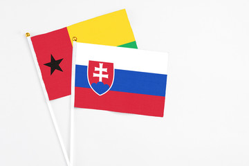 Slovakia and Guinea Bissau stick flags on white background. High quality fabric, miniature national flag. Peaceful global concept.White floor for copy space.
