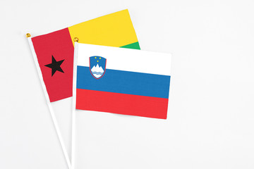 Slovenia and Guinea Bissau stick flags on white background. High quality fabric, miniature national flag. Peaceful global concept.White floor for copy space.