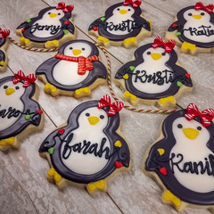Collection of boy and girl personalized Christmas penguins as decorated sugar cookies for gifts with generic names written in frosting