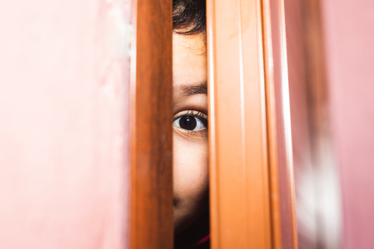 Boy Peeking Behind A Door