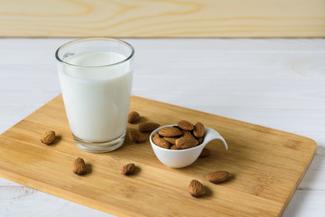 almonds and glass with almond milk on wooden background