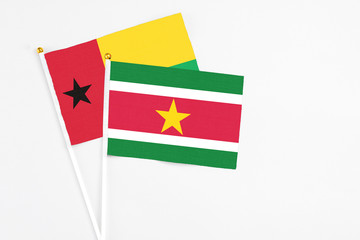 Suriname and Guinea Bissau stick flags on white background. High quality fabric, miniature national flag. Peaceful global concept.White floor for copy space.