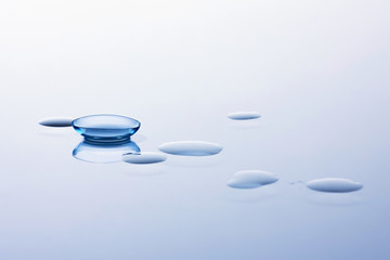 Contact lenses and water drops on light blue background. Eyewear, eyesight, eye care and health,...