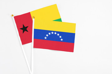 Venezuela and Guinea Bissau stick flags on white background. High quality fabric, miniature national flag. Peaceful global concept.White floor for copy space.